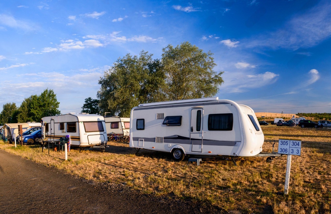 Row of caravans on a grassy campsite under a blue sky